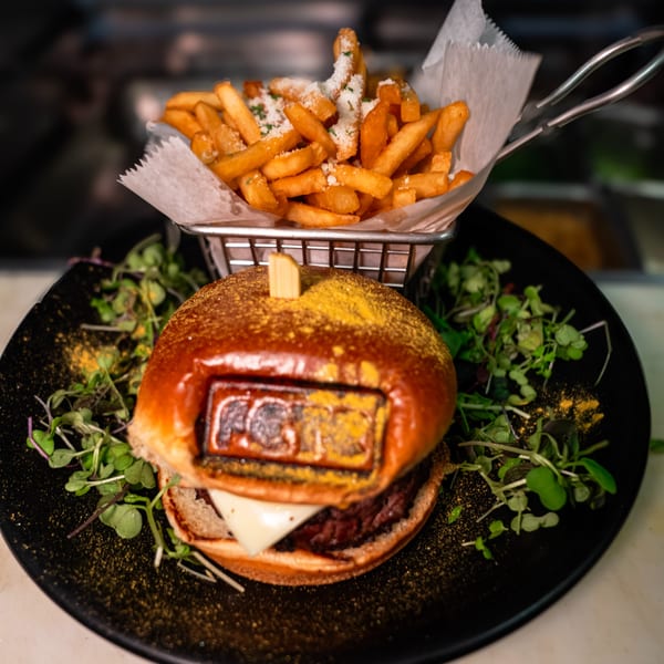 Fete burger with cheese and microgreens, served with a side of parmesan fries.
