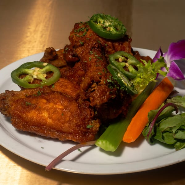 Fete's Caribbean jerk chicken wings, garnished with jalapeños, parsley, and a side salad.